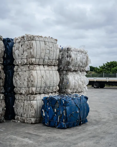 Bales of plastic scrap stacked in a recycling yard.