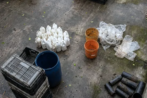 Typical plastic scrap on concrete: milk bottles, a drum, crates, buckets, film, bread bags and pipe offcuts.